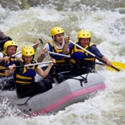 Group of five people whitewater rafting in river